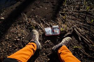 le ouvert premier aide trousse mensonges sur le sol à le pieds de le touristique. une forêt voyageur ouvert une premier aide sac. une ensemble de comprimés et médicaments. photo