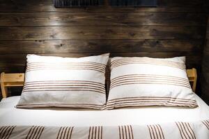 jumelé oreillers fabriqué de doux en tissu avec une géométrique modèle. confortable en bois pièce, profonde dormir. le faible lumière dans le bois chambre. coton lit lin. photo