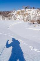 le ombre de une homme contre le Contexte de blanc neige. paysage dans hiver, tranquillité et tranquillité. silhouette de une touristique. photo