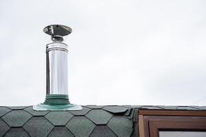 acier tuyau fixé sur le toit de le loger, cheminée dans le bain, imperméabilisation de le toit, métal tuyau pour le poêle, Feu diviseur fin photo