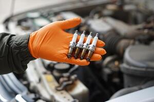 proche en haut mécanicien mains tenir vieux étincelle brancher, de rechange partie de voiture moteur. concept, machine entretien, réparer, réparation, vérifier ou diagnostiquer voiture problèmes par moteur spécialiste. photo