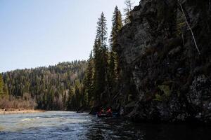 du sud urales touristes radeau le long de le rivière rafting sur le eau, le paysage de une Montagne rivière, une foncé conifère forêt. photo