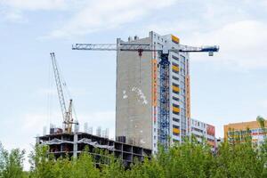 le construction de une Résidentiel bâtiment, une gratte-ciel construction grue travaux à une hauteur, une construction placer, un appartement bâtiment, une Résidentiel trimestre. photo