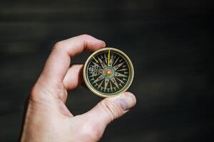 antique boussole dans main. une dispositif cette facilite Voyage. orientation à le magnétique poteaux de le Terre et le cardinal points. photo