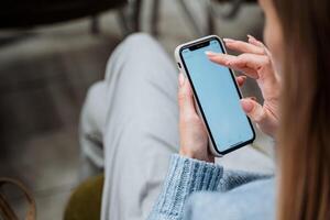 le fille détient le téléphone dans sa mains retournement par le filtrer. le doigt de une femme main presses sur le téléphone intelligent. faire défiler le écran de votre mobile appareil. gadget dans main. photo