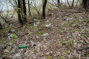 des ordures est un environnement catastrophe pollution, Plastique bouteilles mensonge dans le forêt empoisonnement le Terre, Humain déchets sur le rivière banque. photo