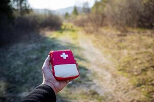 une compact premiers secours trousse, une petit sac avec médicaments, une rouge mobile premier aide trousse, une main détient une ensemble de spécial drogues. photo