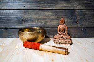 une Tibétain en chantant bol et statue de Bouddha sur le sol. méditation à maison. une matière pour méditation et guérison des sons. Zen pratique.calme et tranquillité photo