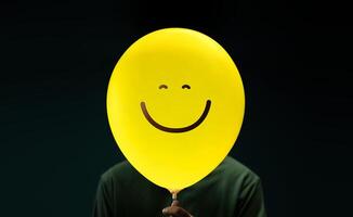 bonheur journée concept. content et optimiste esprit, bien mental santé. profiter la vie tous les jours. bonheur la personne avec une souriant émoticône ballon photo