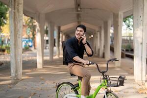 éco amical, content mode de vie asiatique Jeune homme d'affaire balade vélo aller à Bureau travail à ville rue avec vélo dans Matin photo