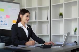 magnifique asiatique femme d'affaires femme en utilisant calculatrice et portable pour Faire la finance sur un Bureau bureau, impôt, rapport, comptabilité, statistiques, et une analyse recherche concept photo