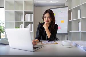 magnifique asiatique femme d'affaires femme en utilisant calculatrice et portable pour Faire la finance sur un Bureau bureau, impôt, rapport, comptabilité, statistiques, et une analyse recherche concept photo