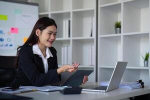 magnifique asiatique femme d'affaires femme en utilisant calculatrice et portable pour Faire la finance sur un Bureau bureau, impôt, rapport, comptabilité, statistiques, et une analyse recherche concept photo