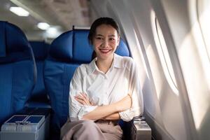 réussi asiatique femme d'affaires ou femelle entrepreneur dans une avion est assis dans une affaires classe siège photo