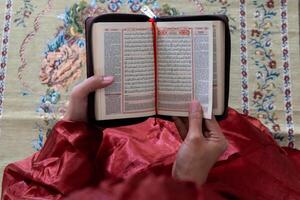 main de une musulman femme en portant le coran avec indonésien Traduction photo