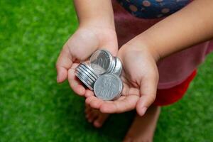 indonésien pièces de monnaie dans mains. asiatique enfant en portant indonésien pièce de monnaie argent. économie argent et investissement concept. photo