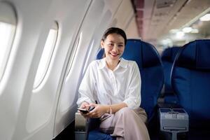 réussi asiatique femme d'affaires ou femelle entrepreneur dans une avion est assis dans une affaires classe siège photo