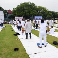 Nouveau Delhi, Inde, juin 21, 2023 - groupe yoga exercice session pour gens à yamuna des sports complexe dans delhi sur international yoga jour, gros groupe de adultes assister yoga classe dans criquet stade photo