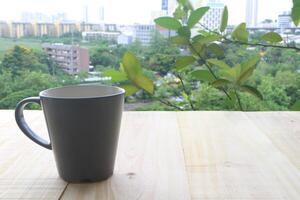 café tasse sur en bois table dans le terrasse. à la recherche en dehors à le paysages urbains. photo