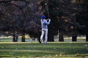 Carmichael, Californie, 2015 - Masculin golfeur après balançoire sur le golf cours parmi des arbres photo