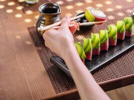 fille en mangeant Sushi Rouleaux enveloppé avec thon et Avocat photo