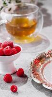 framboises dans une bol et une verre tasse de thé photo