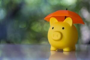 Jaune porcin banque avec Orange parapluie concept pour la finance assurance, protection photo