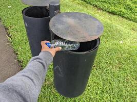 homme jeter bouteille sur le ordures poubelle. le photo est adapté à utilisation pour environnement et Publique parc contenu médias.