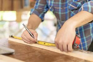 homme propriétaire une petit meubles affaires est en train de préparer bois pour production. Charpentier Masculin est régler bois à le voulu taille. architecte, designer, intégré, professionnel bois, artisan, atelier. photo