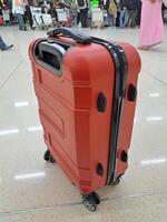une rouge valise avec noir lignes sur le fermeture éclair et roues est très adapté pour longue voyages ou Voyage photo
