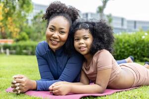 africain américain mère et Jeune fille sont mensonge vers le bas après ayant yoga exercice dans Publique parc commun zone espace pour fin de semaine loisir et bonheur concept photo