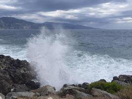 une grand vague éclaboussures contre le rochers sur le rive photo