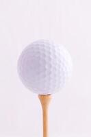 le golf Balle fermer sur en bois tee contre lumière arrière-plan photo