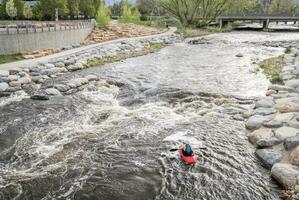 solitaire kayakiste surfant le vague dans eau vive parc sur le poudre rivière dans centre ville de fort collins, Colorado photo