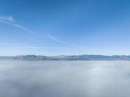 dense brouillard couvrant collines de nord Colorado avec clair montagnes à une horizon, aérien vue de hiver Matin photo