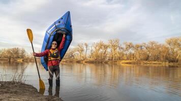 content Sénior Masculin pagayeur est permanent avec un gonflable packraft et pagayer sur une Lac rive dans de bonne heure printemps printemps dans nord Colorado photo
