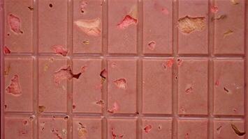 une bar de rose rubis Chocolat avec lyophilisé des fraises et amandes fermer. une en bonne santé dessert basé sur baies et des noisettes photo