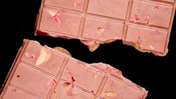 une bar de rose rubis Chocolat avec lyophilisé des fraises et amandes fermer, isolé noir Contexte. une en bonne santé dessert basé sur baies et des noisettes photo