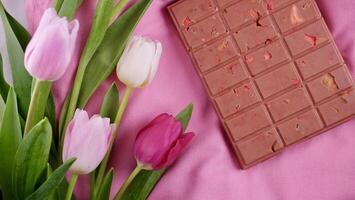 une bar de rose rubis Chocolat avec sublimé lyophilisé des fraises et amandes et printemps tulipe fleurs . une dessert basé sur baies et des noisettes pour international aux femmes jour, Mars 8, de la mère journée photo