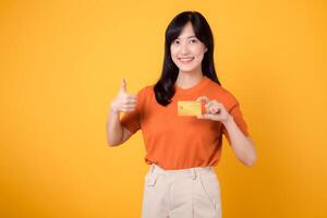 sur de soi Jeune asiatique femme 30s en portant une crédit carte, permanent isolé sur vibrant Jaune Contexte. sécurise en ligne Paiement concept photo