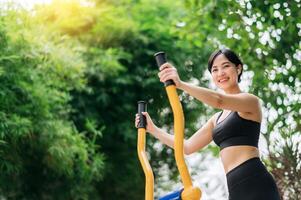 Jeune asiatique athlétique sportive 30s portant tenue de sport écoute relaxant la musique tandis que travail en dehors exercice équipement Extérieur dans parc. en bonne santé mode de vie concept photo