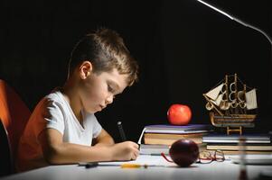 garçon apprendre cours dans le Accueil réglage à le table dans le lumière de une table lampe. photo