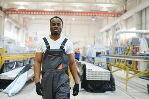 africain Masculin ingénieur. contrôle une Matériel production machine système, travail dans une Plastique et acier industrie En ce qui concerne le de l'entreprise produit entreprise. photo