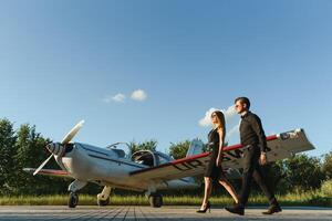 magnifique Jeune élégant couple dans officiel vêtements est permanent près privé avion. photo