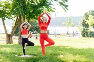 mère et fille Faire yoga des exercices sur herbe dans le parc à le journée temps photo