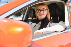 Femme d'affaires réussie au volant de voiture à travers une ville urbaine moderne avec des reflets de bâtiments photo