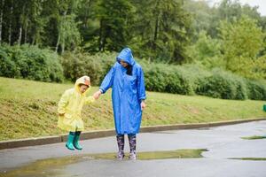 mère et enfant, garçon, en jouant dans le pluie, portant bottes et imperméables photo