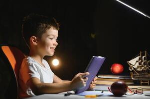 garçon apprendre cours dans le Accueil réglage à le table dans le lumière de une table lampe. photo