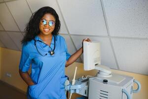 Jeune afro américain femelle médecin permanent dans clinique Bureau près moderne ultrason machine. photo