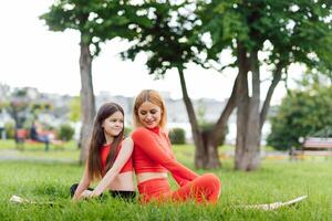 mère et fille Faire yoga des exercices sur herbe dans le parc à le journée temps photo